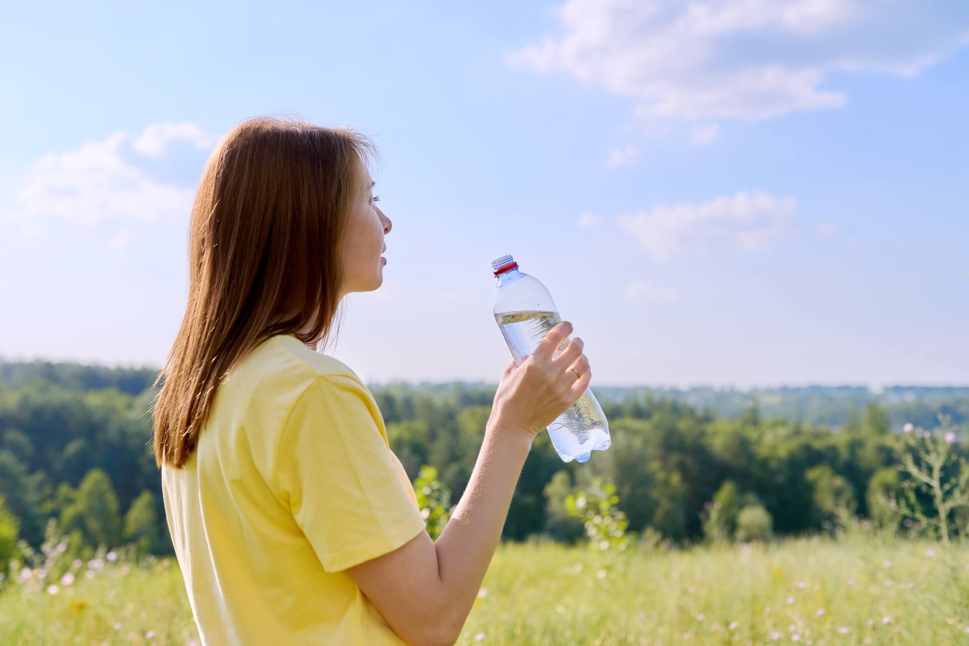 chaude journée d'été femme adulte assoiffée buvant de l'eau