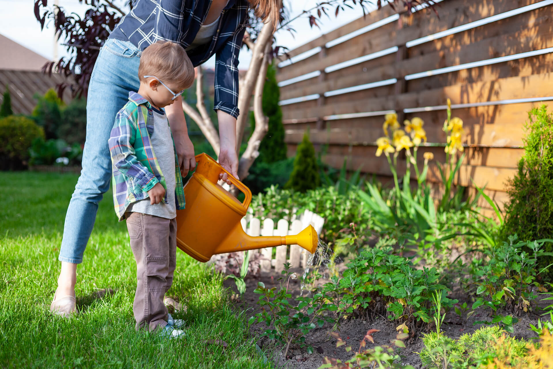 enfant et mere avec un arrosoir arrosant un jardin